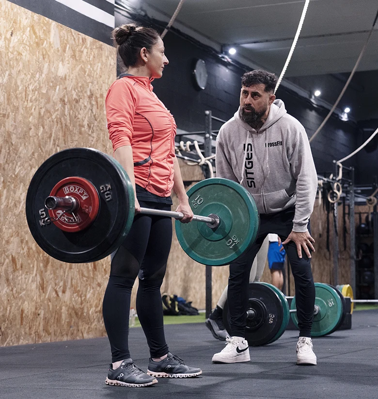 mujer levantando pesas con entrenador