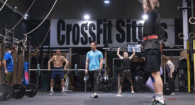 interior de gimnasio con personas levantando peso